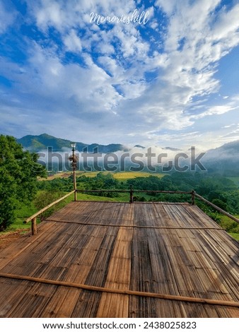 Morning landscape, bright sky, green mountains, and white mist streaking across the mountains. bamboo courtyard floor in front of the hill tribe house Missing the good weather in Chiang Mai, Thailand.