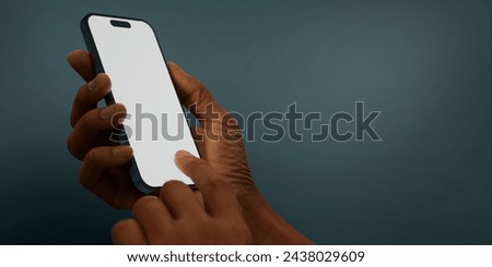 Black African-American hand displays a modern smartphone with a blank screen against a deep teal background, ideal for presenting apps or mobile interfaces in a clean and contemporary setting Royalty-Free Stock Photo #2438029609