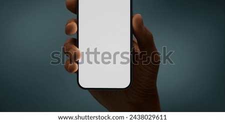 Black African-American hand displays a modern smartphone with a blank screen against a deep teal background, ideal for presenting apps or mobile interfaces in a clean and contemporary setting Royalty-Free Stock Photo #2438029611