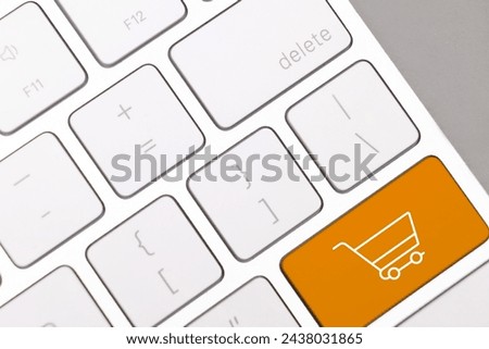 Internet store. Orange button with shopping cart on computer keyboard, top view