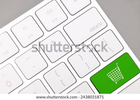 Internet store. Green button with shopping cart on computer keyboard, top view