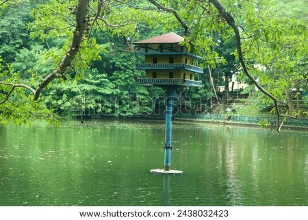 Pigeon cage in the middle of the lake at Gadjah Mada University surrounded by lush trees. Lake park in the city with pigeon house Royalty-Free Stock Photo #2438032423