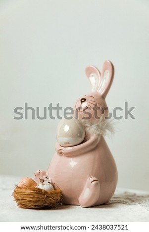 Easter bunny with white eggs standing on a white tablecloth.