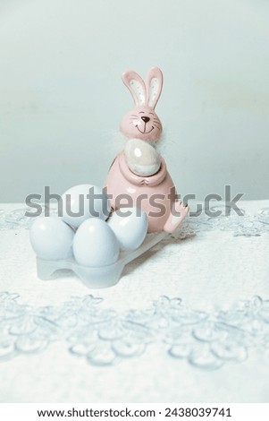 Easter bunny with white eggs standing on a white tablecloth