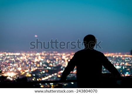 Silhouette of man looking above the city in the night Royalty-Free Stock Photo #243804070