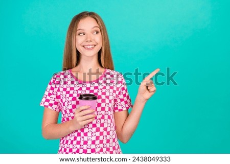 Photo portrait of pretty teenager girl paper cup point look empty space wear trendy print pink clothes isolated on cyan color background