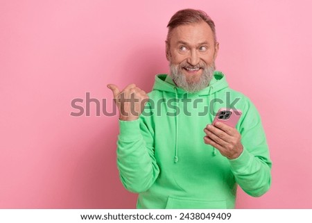 Photo of funky cheerful man wear green sweatshirt typing modern gadget thumb empty space isolated pink color background
