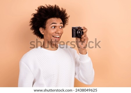 Photo of positive excited man wear white clothes make picture hold camera look objective isolated on beige color background