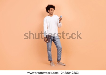 Full length photo of cheerful man wear stylish clothes chatting using modern technology wifi connection isolated on beige color background