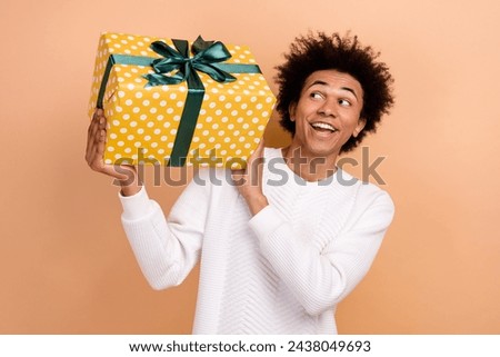 Photo of optimistic nice man wear white trendy jumper hands hold gift good mood isolated on beige color background