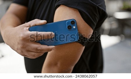Confident young latin man harnessing technology, scanning his diabetes sensor with smartphone on city street, monitoring glucose levels with a smile Royalty-Free Stock Photo #2438062057