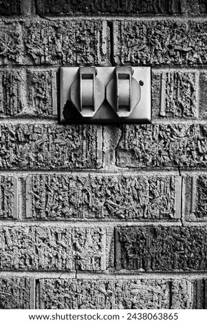 A vintage electrical cover outlet on a brick wall in a black and white.