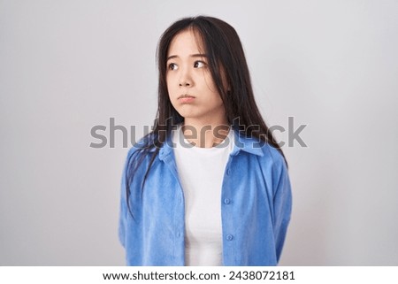 Young chinese woman standing over white background looking sleepy and tired, exhausted for fatigue and hangover, lazy eyes in the morning. 