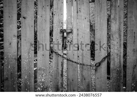 Weathered wooden gate locked with hasp and chain Royalty-Free Stock Photo #2438076557