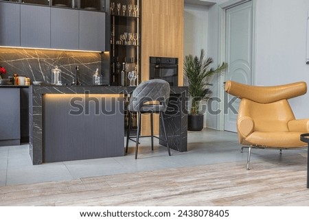 wood decorated dark kitchen area with coocking island in huge modern spacious apartment with high loft style ceilings, wooden decoration and grey walls