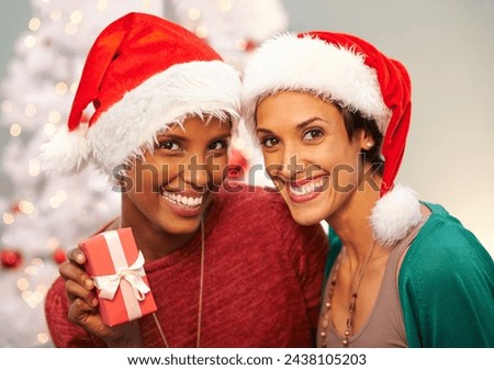 Friends, gift and portrait by Christmas tree in home, smile and bonding for festive season. Women, religious holiday and present for celebration in living room, hat and tradition on vacation or box