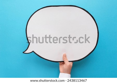 Empty speech bubble in hand wearing white shirt on a blue background. Comic cloud with a place for text
