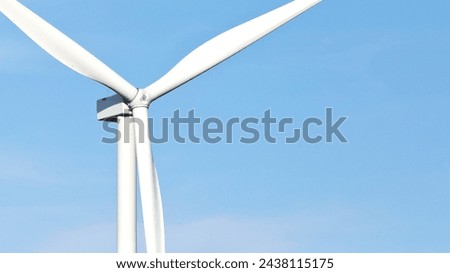 Close-up color photo of large wind turbine blades against a blue sky background with copy space.