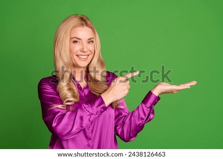 Photo of stunning cheerful lady toothy smile indicate finger arm hold empty space ad isolated on green color background