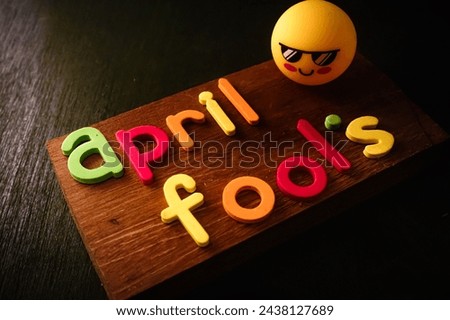 April fool's day Concept , colorful text on wooden background with cool face expression emoji