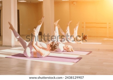 Well looking middle aged sporty woman, fitness instructor in pink sportswear doing stretching and pilates on yoga mat in the studio with mirror. Female fitness yoga. Healthy lifestyle and harmony.