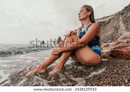 Woman summer travel sea. Happy tourist in blue bikini enjoy taking picture outdoors for memories. Woman traveler posing on the beach surrounded by volcanic mountains, sharing travel adventure journey