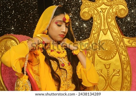 Portrait of a beautiful Indian female model in yellow saree with light makeup and jewellery made of flowers. Its a wedding dress and makeup of Indian bride for Haldi function in Indian culture.