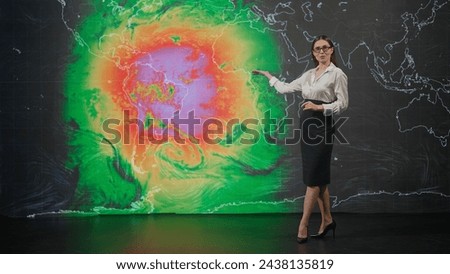 Female presenter in the studio. Woman anchor news host presenting weather forecast, reporting on air, virtual climate map graphic background at the back.