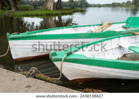 Pair of wooden, hand built canoes seen mored up on a large boating lake in England. The boats are available to the public for hire.