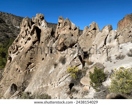 Bandelier National Monument in New Mexico. Hot ash from volcano at Valles Caldera cooled and welded into a rock called tuff. Pajarito Plateau and Frijoles Canyon show Volcanic Geology.  Royalty-Free Stock Photo #2438154029
