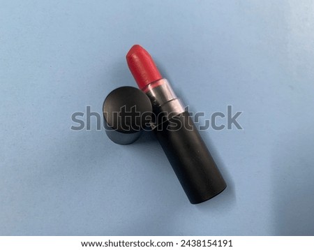 Red lipstick in black jacket package on blue background 
