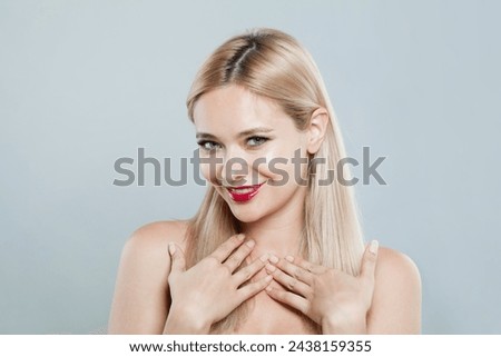 Excited fashion female model with long blonde hairstyle and shiny fresh skin on white background, studio portrait 