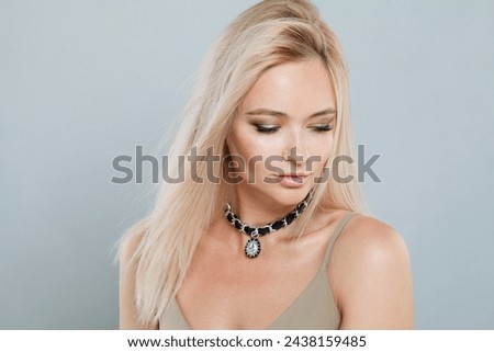 Cute young good-looking female model with long colored hair and healthy skin portrait. Blonde woman looking at camera on gray studio wall background