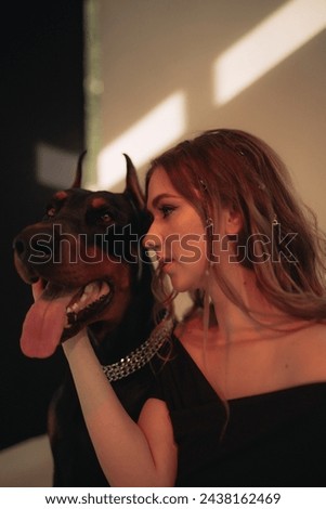 Girl cuddled with black dog, Doberman pinscher in a photo in a spacious photo studio