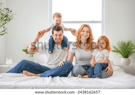 A happy family mother, father and children having fun in bed in bedroom at home