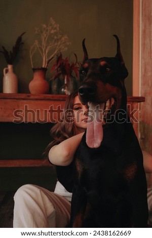Girl cuddled with black dog, Doberman pinscher in a photo in a spacious photo studio