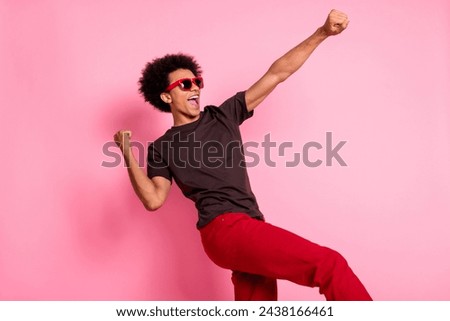 Photo of overjoyed young happy guy wear sunglasses raised fists up celebrate triumph dancing isolated on pink color background