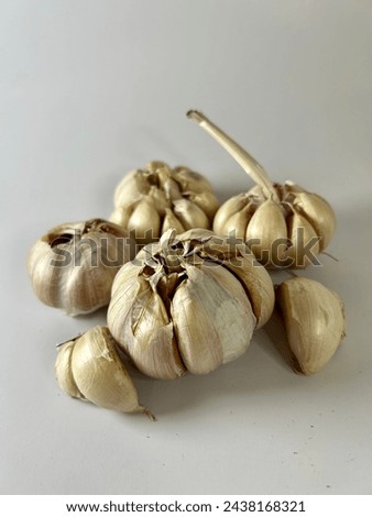 A cluster of intact, unpeeled garlic bulbs is depicted alongside a few cloves already peeled. Royalty-Free Stock Photo #2438168321