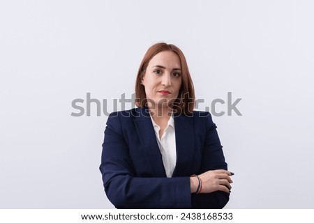 Portrait of a young, red-haired, lesbian businesswoman dressed in jacket suit and a rainbow flag bracelet on her wrist. White background and copy space. Concept of equality, rights and LGTBI pride