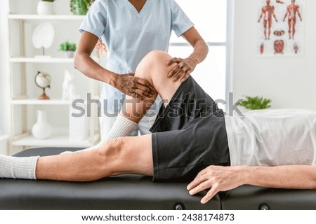 A black Physiotherapist helping senior man with in clinic. Elderly man undergoing physiotherapy treatment for injury