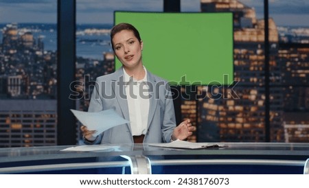 Female news presenter reporting in broadcasting studio. Positive woman checking papers with text alone at green screen display newsroom. Expert anchor talking at mockup chroma key picture background