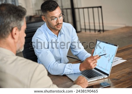 Financial advisor explaining invest stock market data consulting investor. Two busy business men analysts doing finance trading analysis pointing at exchange chart on laptop screen working in office. Royalty-Free Stock Photo #2438190465