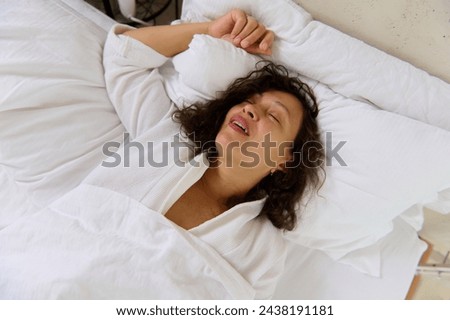 Close-up of a young woman snoring while sleeping in her bed. Snoring problems. Multi ethnic young adult woman having insomnia and health problems, falling asleep in her bed in bedchamber Royalty-Free Stock Photo #2438191181