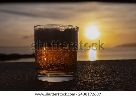 Selective focus of beer glass with scenic sunset view of Dalmatian archipelago seen from coastal town Makarska, Split-Dalmatia, Croatia, Europe. Coastline of Makarska Riviera, Adriatic Sea in summer Royalty-Free Stock Photo #2438192689