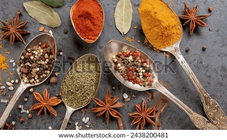A circle of wooden spoons holding an array of assorted spices rests on a rustic stone tabletop. This vibrant display resembles an exotic Oriental spice market, brimming with colorful herbs and season. Royalty-Free Stock Photo #2438200481