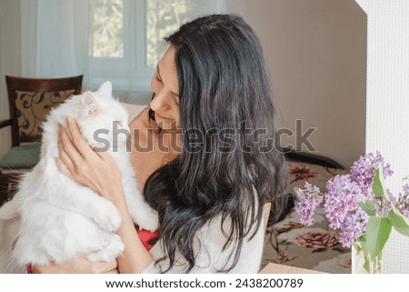 A middle-aged woman shares a tender moment with her white cat at home, suggesting themes of midlife, and the importance of emotional support animals and love. High quality photo