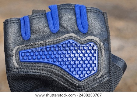 one blue black leather cycling glove on a gray background outdoors
