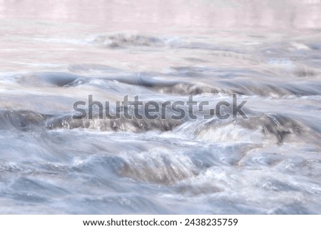 Pastel colored water rushing over rocks long exposure photography of a stream