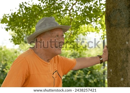 An old Asian man is happily visiting the park