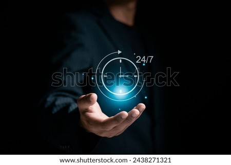 Nonstop customer service concept. Businessman holding clock icon with 24-7 on virtual screen for worldwide nonstop and full-time available contact of service.  Royalty-Free Stock Photo #2438271321